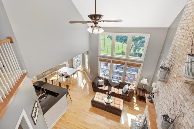 living room featuring light wood-style floors, ceiling fan, and high vaulted ceiling