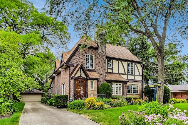 tudor house featuring a garage, an outdoor structure, and a front yard