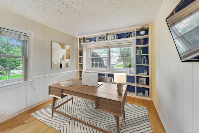 office featuring wood walls, ornamental molding, a textured ceiling, and light hardwood / wood-style flooring