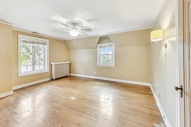 additional living space featuring radiator heating unit, light hardwood / wood-style flooring, ceiling fan, and lofted ceiling