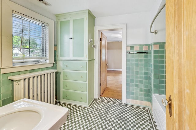 bathroom with shower / bathtub combination, radiator, and tile walls