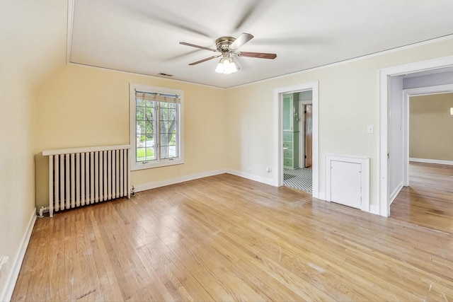 empty room with ceiling fan, radiator heating unit, and light hardwood / wood-style flooring