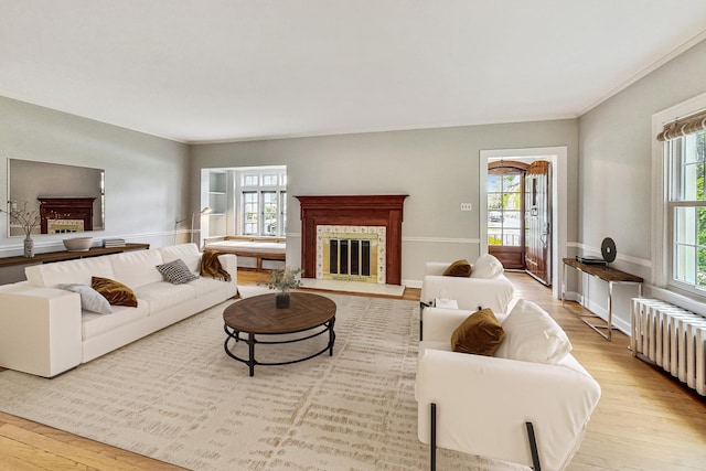 living room featuring radiator heating unit, ornamental molding, and light hardwood / wood-style flooring