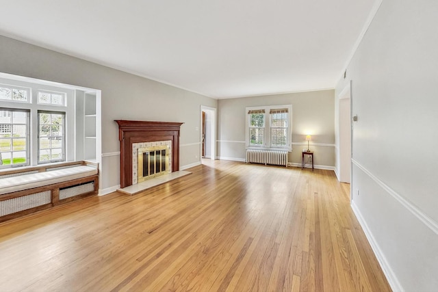 unfurnished living room featuring light wood-type flooring, radiator heating unit, and crown molding