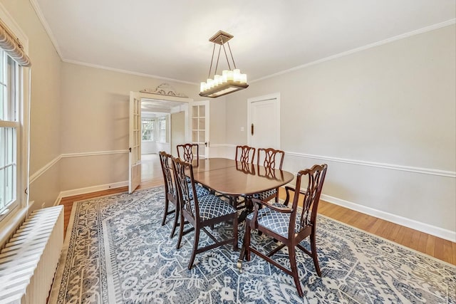 dining area with hardwood / wood-style floors, plenty of natural light, crown molding, and french doors