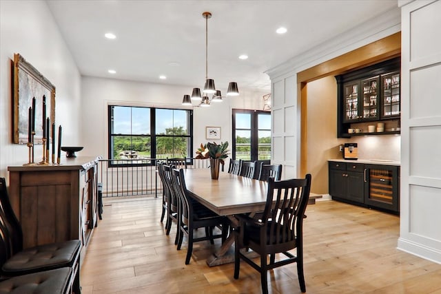 dining area featuring a notable chandelier, bar area, beverage cooler, and light wood-type flooring