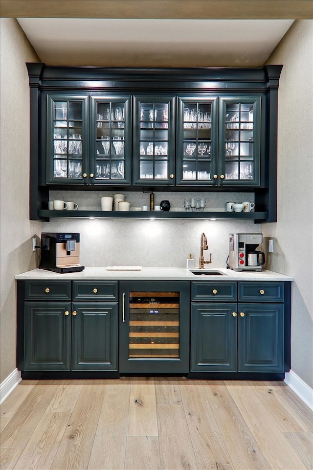 bar with sink, beverage cooler, light wood-type flooring, and decorative backsplash