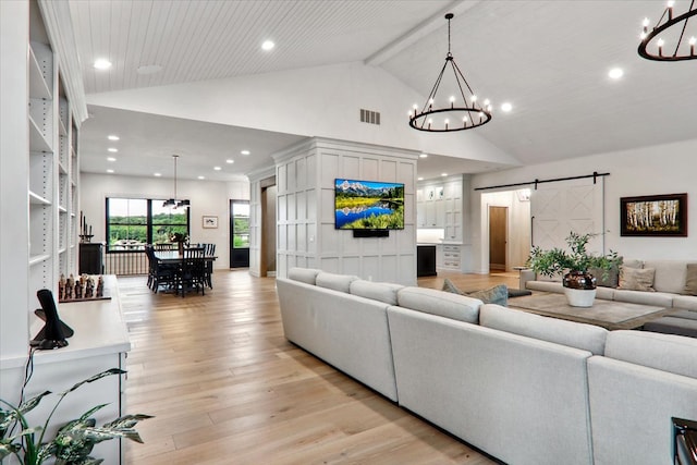 living room featuring a barn door, a chandelier, high vaulted ceiling, and light hardwood / wood-style flooring