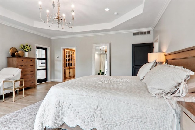 bedroom with a notable chandelier, crown molding, light hardwood / wood-style floors, and a raised ceiling