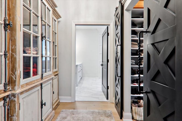 hall with a barn door and light wood-type flooring