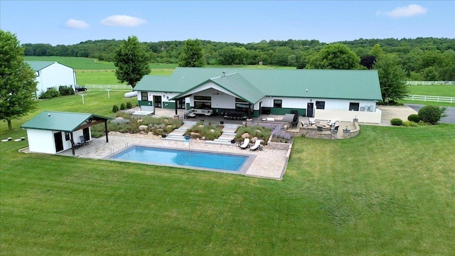 rear view of property with a patio, an outdoor structure, exterior bar, and a lawn