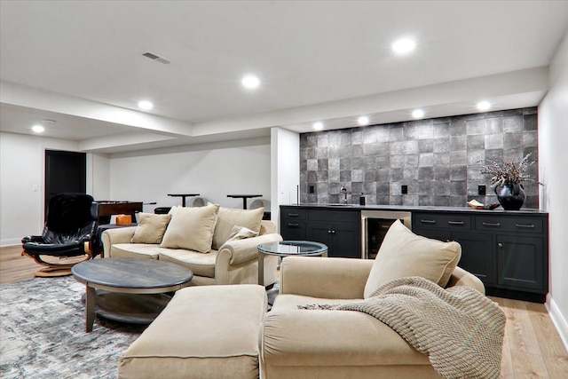 living room with light hardwood / wood-style flooring, wet bar, and beverage cooler