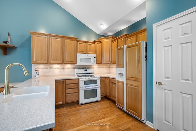 kitchen with light wood-type flooring, white appliances, sink, vaulted ceiling, and backsplash