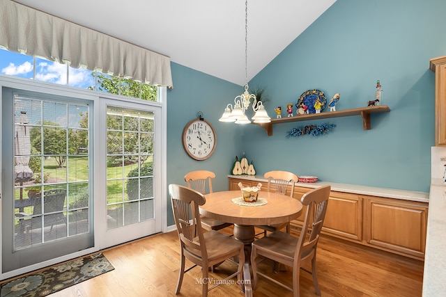 dining room with light hardwood / wood-style floors, high vaulted ceiling, and an inviting chandelier