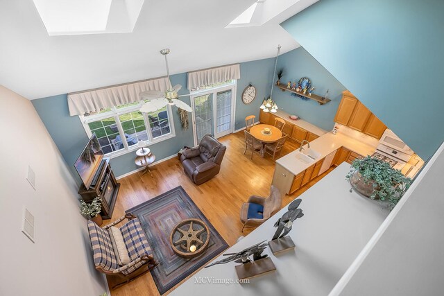 living room featuring sink, a skylight, high vaulted ceiling, ceiling fan, and wood-type flooring