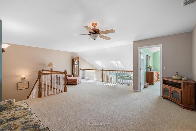 additional living space with lofted ceiling with skylight, ceiling fan, and light colored carpet