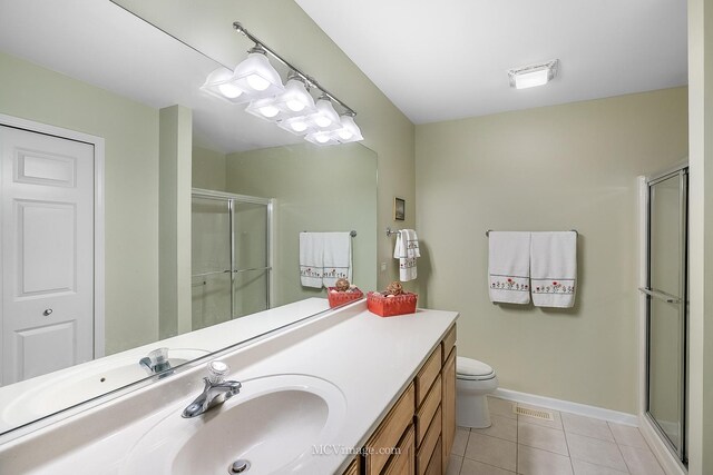 bathroom with tile patterned flooring, a shower with door, toilet, and vanity