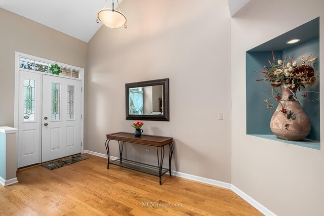 foyer entrance with light hardwood / wood-style floors and lofted ceiling