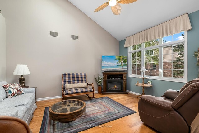 living room with high vaulted ceiling, ceiling fan, and light wood-type flooring