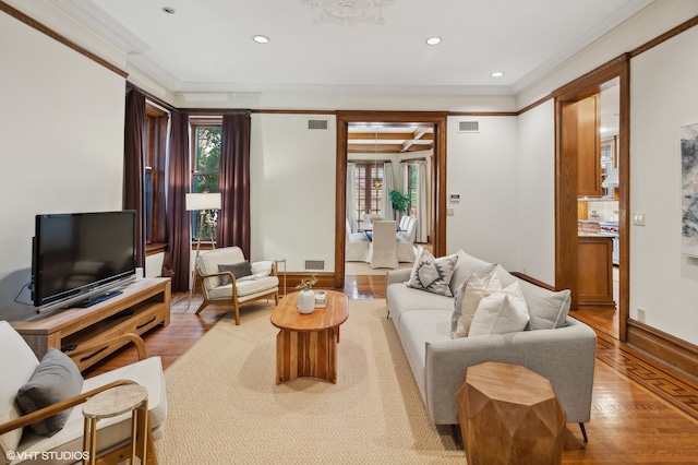 living room with light hardwood / wood-style floors, ornamental molding, and a healthy amount of sunlight