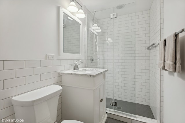 bathroom featuring tile walls, vanity, toilet, and a shower with door