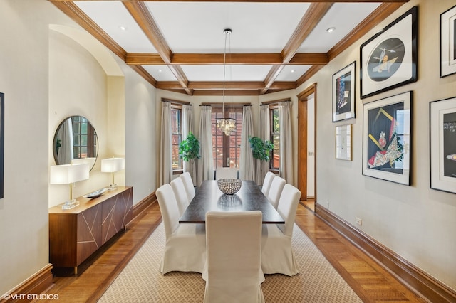 dining area featuring coffered ceiling, beamed ceiling, light wood-type flooring, and an inviting chandelier