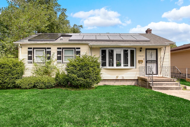 view of front of property featuring a front lawn and solar panels