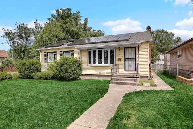 view of front of home with a front yard and solar panels