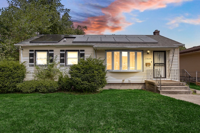 view of front of house with solar panels and a lawn