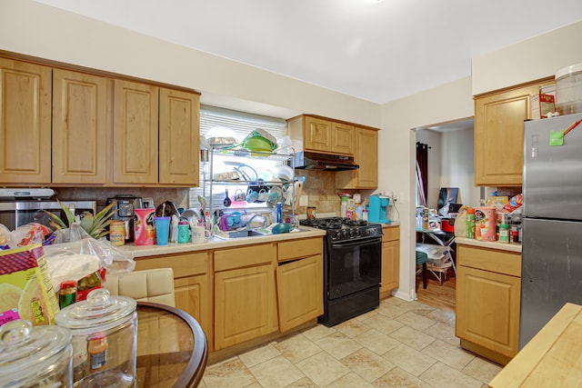 kitchen featuring black gas range, backsplash, sink, light hardwood / wood-style flooring, and stainless steel refrigerator