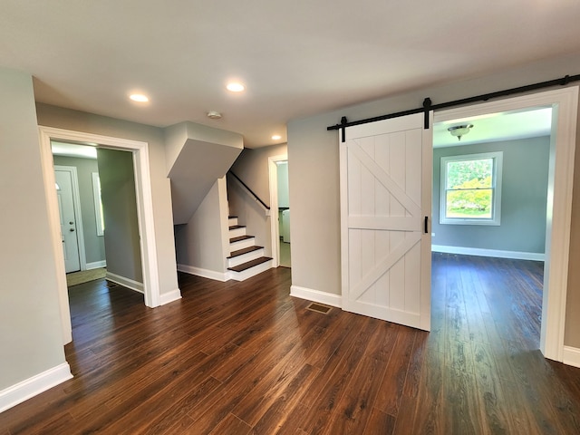 interior space with a barn door and dark hardwood / wood-style floors