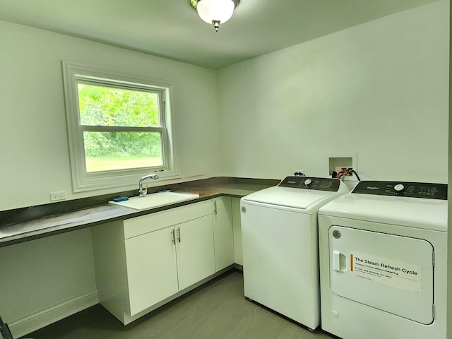 laundry area featuring sink, washing machine and dryer, and cabinets