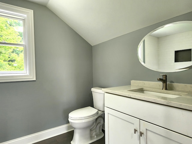 bathroom featuring vanity, toilet, a wealth of natural light, and vaulted ceiling