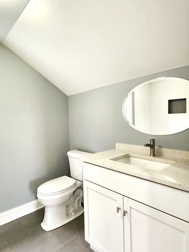 bathroom with vanity, tile patterned floors, toilet, and vaulted ceiling