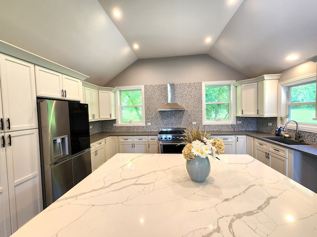 kitchen with lofted ceiling, tasteful backsplash, stainless steel appliances, wall chimney exhaust hood, and sink