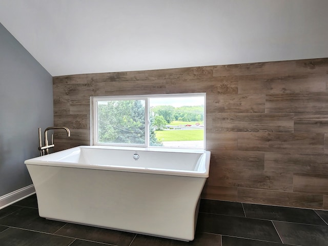 bathroom featuring lofted ceiling, tile patterned flooring, and a bath