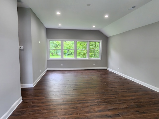 spare room featuring dark wood-type flooring and vaulted ceiling