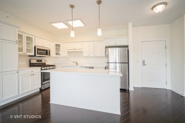 kitchen with dark wood-type flooring, pendant lighting, white cabinets, and stainless steel appliances