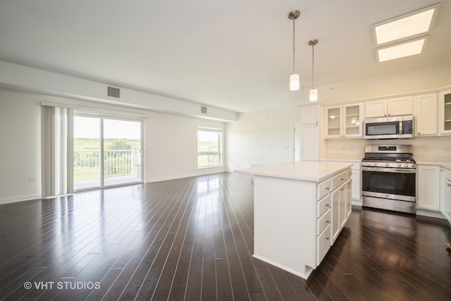 kitchen with decorative light fixtures, stainless steel appliances, white cabinets, a skylight, and dark wood-type flooring