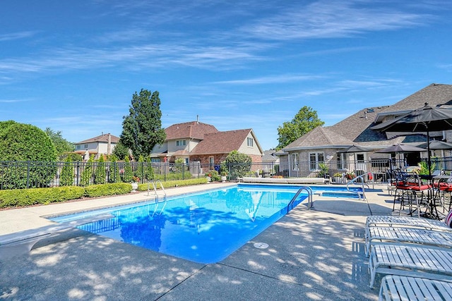 view of swimming pool with a patio area, a residential view, fence, and a fenced in pool