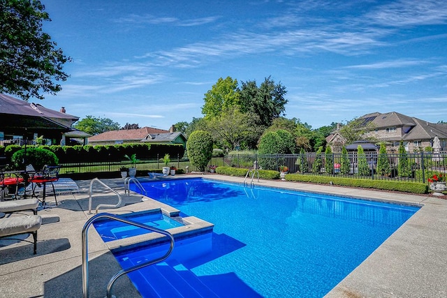 view of swimming pool with a patio area, a pool with connected hot tub, and fence