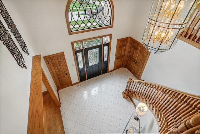 foyer entrance with light tile patterned floors, a high ceiling, stairs, and an inviting chandelier