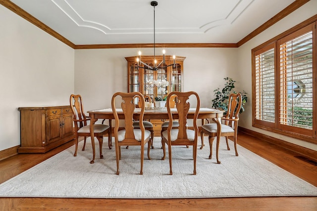 dining room with baseboards, a notable chandelier, ornamental molding, and wood finished floors