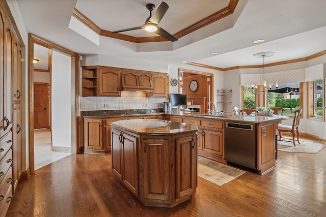 kitchen featuring dishwasher, brown cabinets, a peninsula, a tray ceiling, and a sink