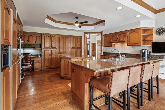 kitchen with a raised ceiling, built in desk, a breakfast bar area, and open shelves