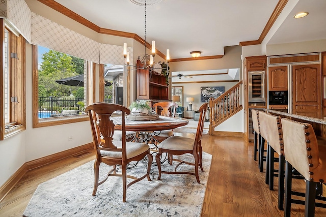 dining area with beverage cooler, baseboards, stairs, light wood-style floors, and ornamental molding