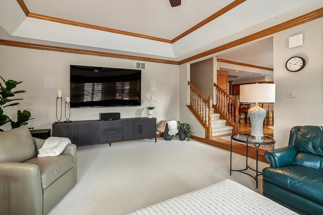 living room with a tray ceiling, visible vents, ornamental molding, carpet flooring, and stairs