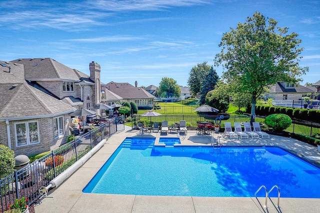 view of pool featuring a fenced in pool, a yard, a patio area, fence, and a residential view