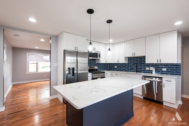 kitchen featuring white cabinets, hardwood / wood-style flooring, hanging light fixtures, and appliances with stainless steel finishes