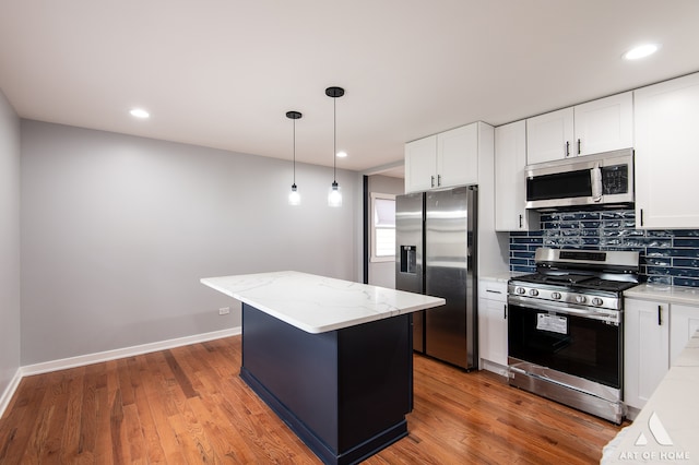 kitchen with stainless steel appliances, light stone counters, pendant lighting, a center island, and hardwood / wood-style flooring